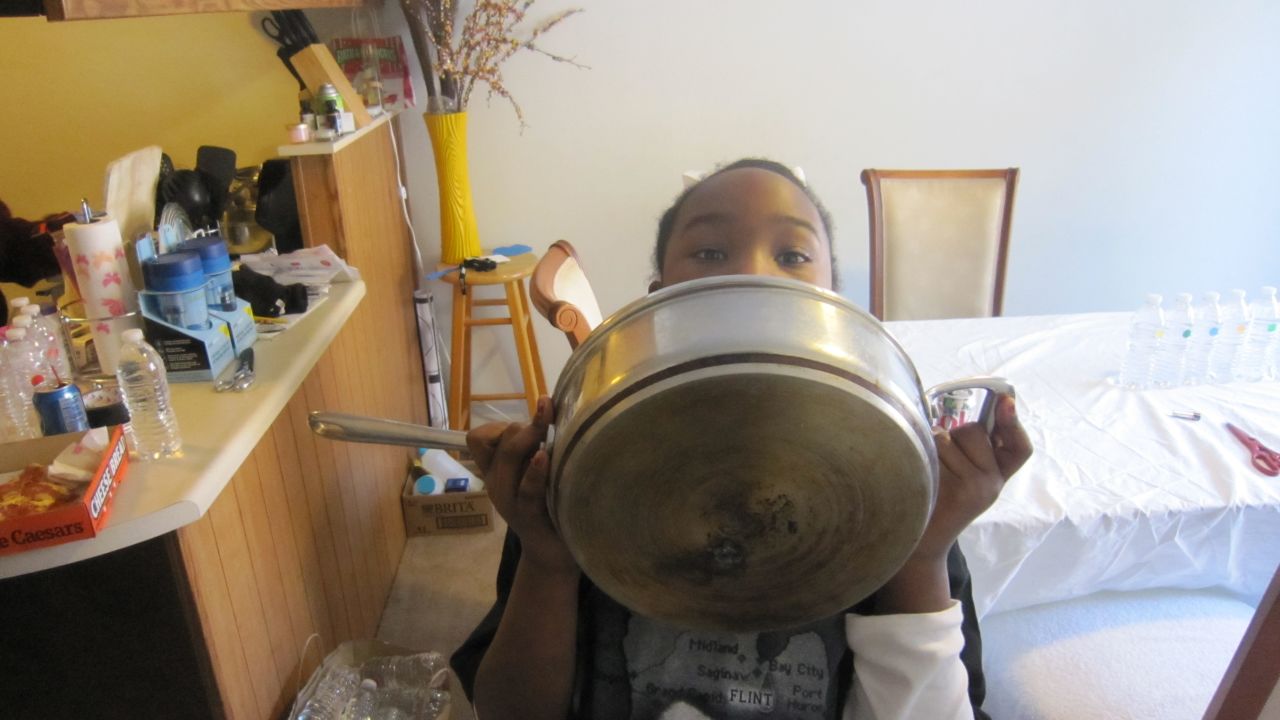 Kennedy Luster, 7, holds a pot her mother says was ruined by washing it in Flint's water.