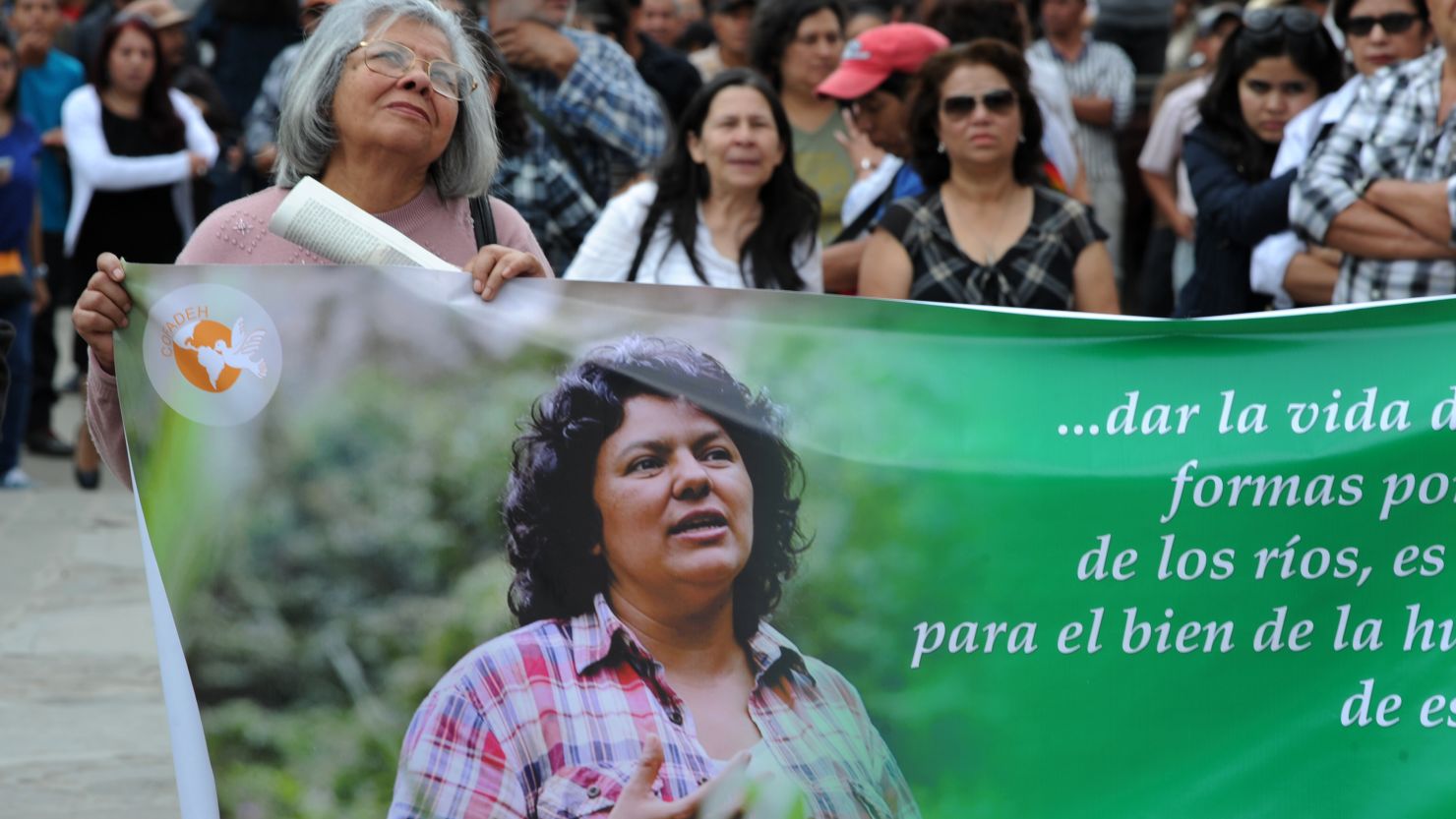 A mourner carries a banner depicting slain activist Berta Cáceres at her funeral.