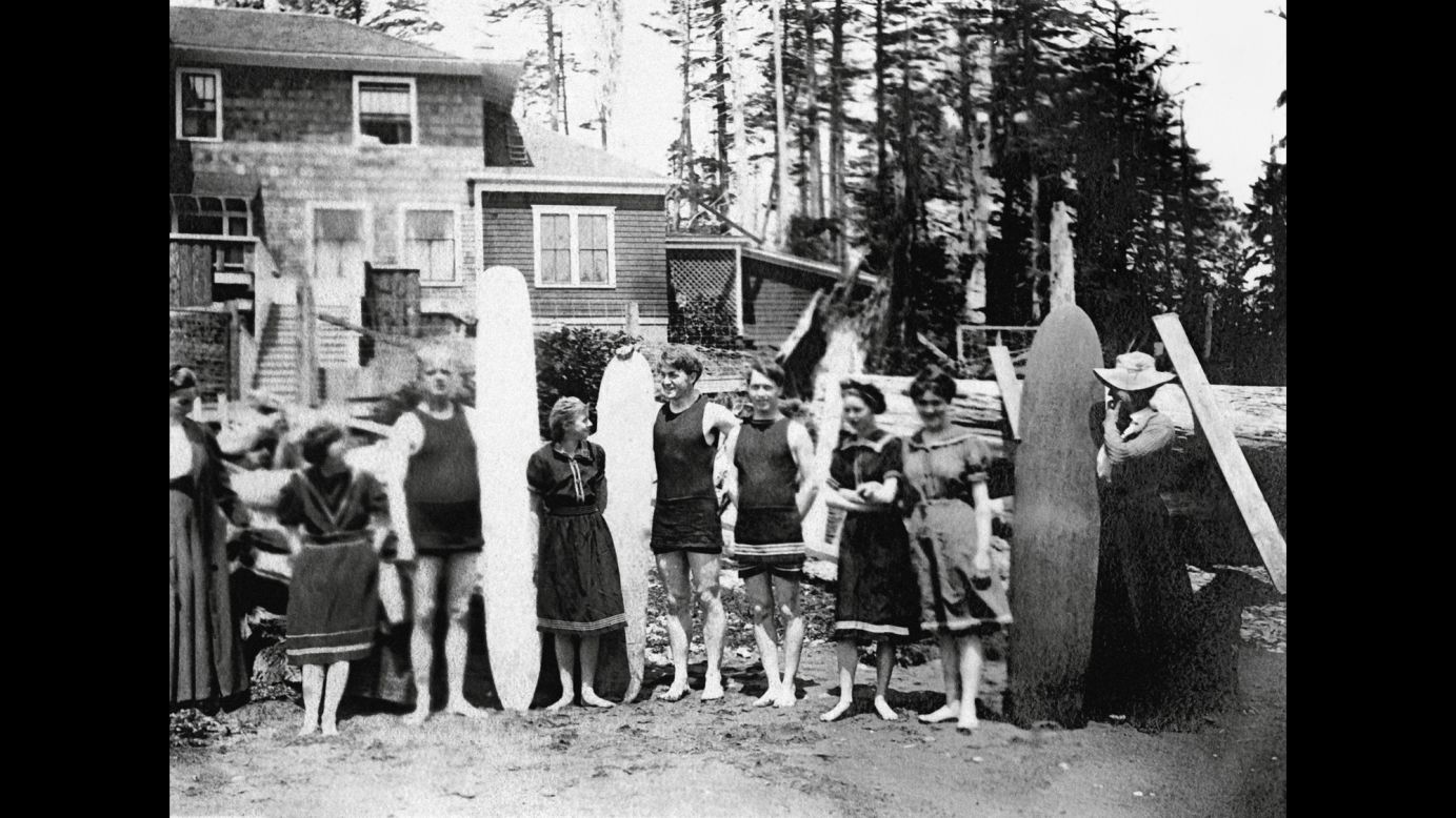 People with surfboards stand in front of a beach house in Joe Creek, Washington, around 1910. Surfing made its way to the Pacific Northwest via descendants of the Dole family of Hawaii, who built a sawmill and shingle factory near the Washington coast. They called it the Aloha Shake Company.