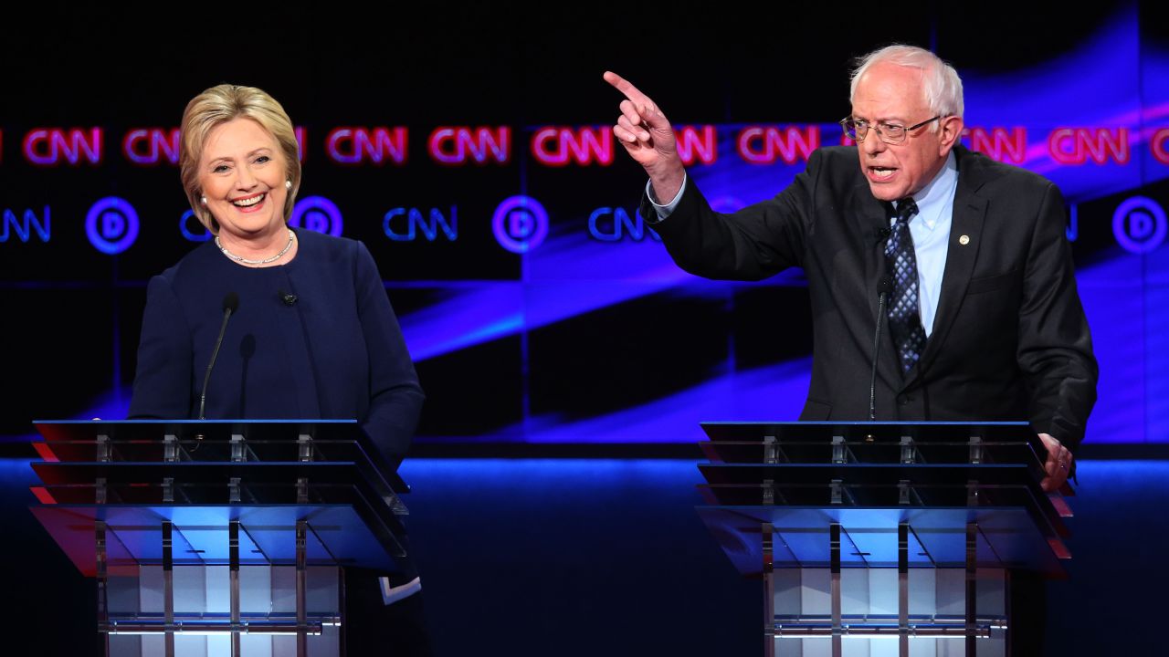 FLINT, MI - MARCH 06:  Democratic presidential candidate Senator Bernie Sanders (D-VT) and Democratic presidential candidate Hillary Clinton speak during the CNN Democratic Presidential Primary Debate at the Whiting Auditorium at the Cultural Center Campus on March 6, 2016 in Flint, Michigan. Voters in Michigan will go to the polls March 8 for the state's primary.  (Photo by Scott Olson/Getty Images)