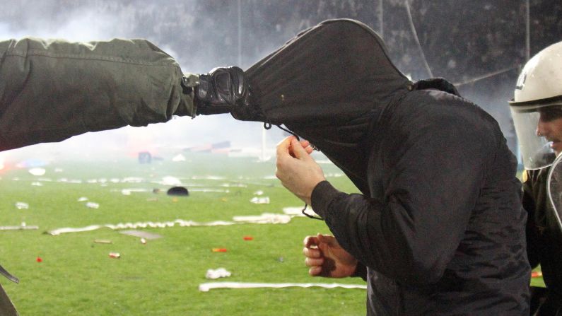 Riot police detain a fan during a Greek Cup soccer match in Thessaloniki on Wednesday, March 2. The semifinal match between Olympiakos and PAOK was stopped in the final minute after angry PAOK fans threw flares onto the field and clashed with police.