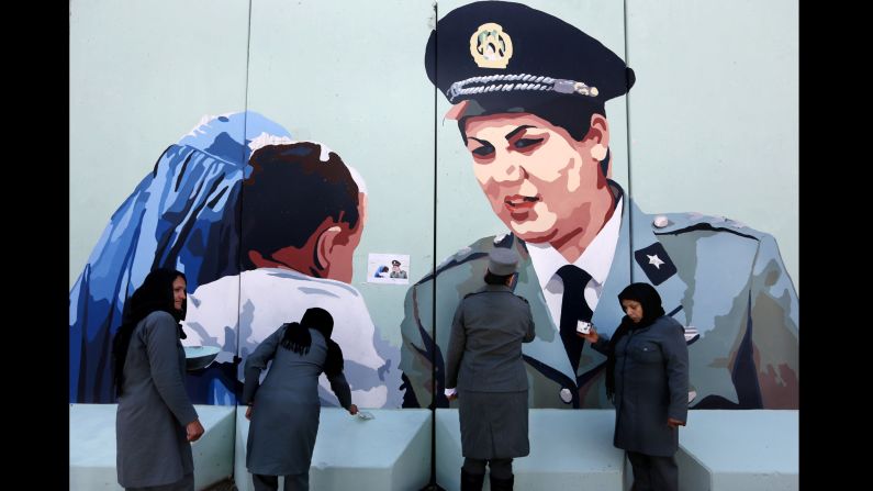Police Officer Friba Hameed, second from right, helps paint a mural of herself outside the main gate of a police precinct in Kabul, Afghanistan, on March 8.