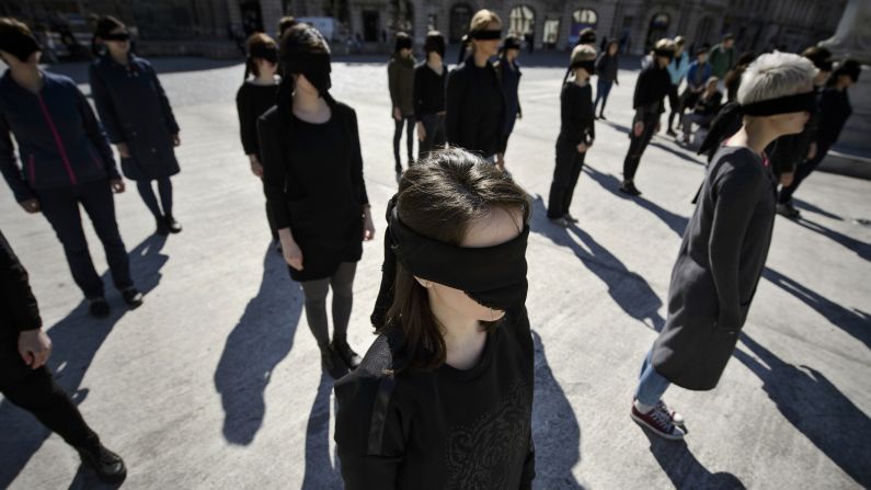 Activists stand blindfolded in Bucharest, Romania, during a March 8 performance honoring the history of feminist movements.