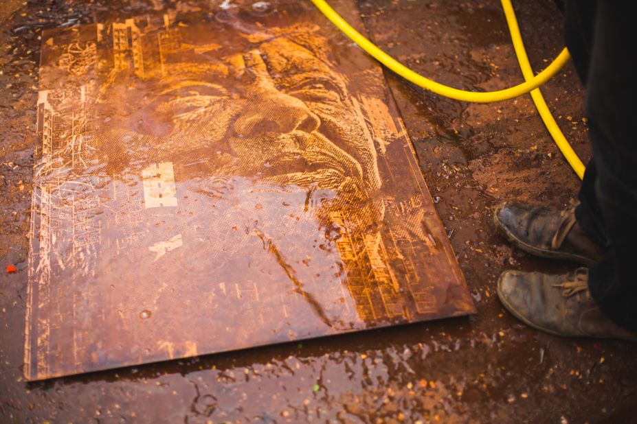 An etched metal plate being washed after an acid bath. 