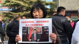 Dai Shuqin's sister's family of five were on MH370. The piece of paper she holds up reads: "President Xi will help us! The country will help us. There will be good news about our loved ones."