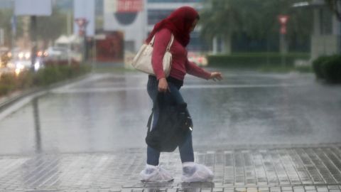 A woman covers her shoes with plastic bags from the rain Wednesday in Dubai.