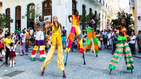 A band and a group of stilt dancers whip around the streets of Old Havana, attracting crowds of visitors. Though Americans are finally normalizing relations with Cuba, tourists from South America, Canada and Europe have been visiting for generations.