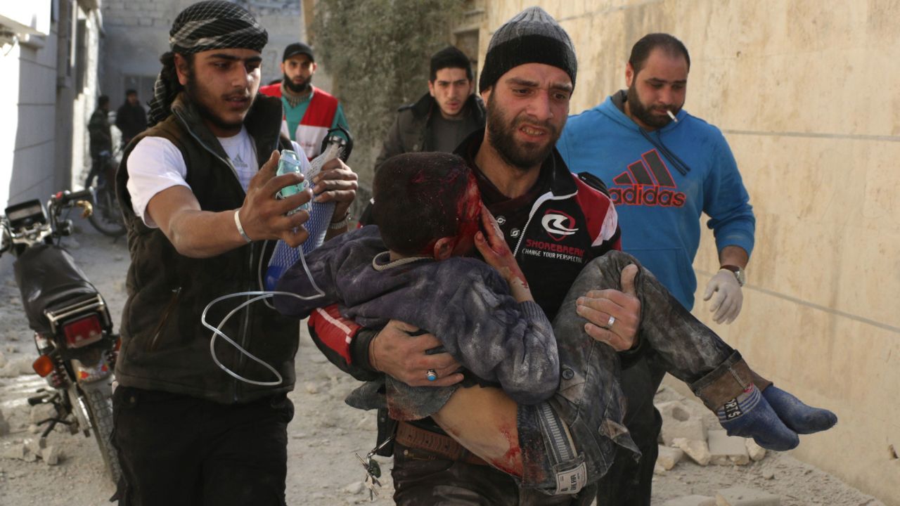 Men treat a child after an airstrike on a residential area of Aleppo in February.