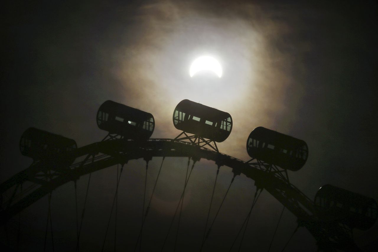 A partial solar eclipse is seen behind passenger capsules of the Singapore Flyer. 