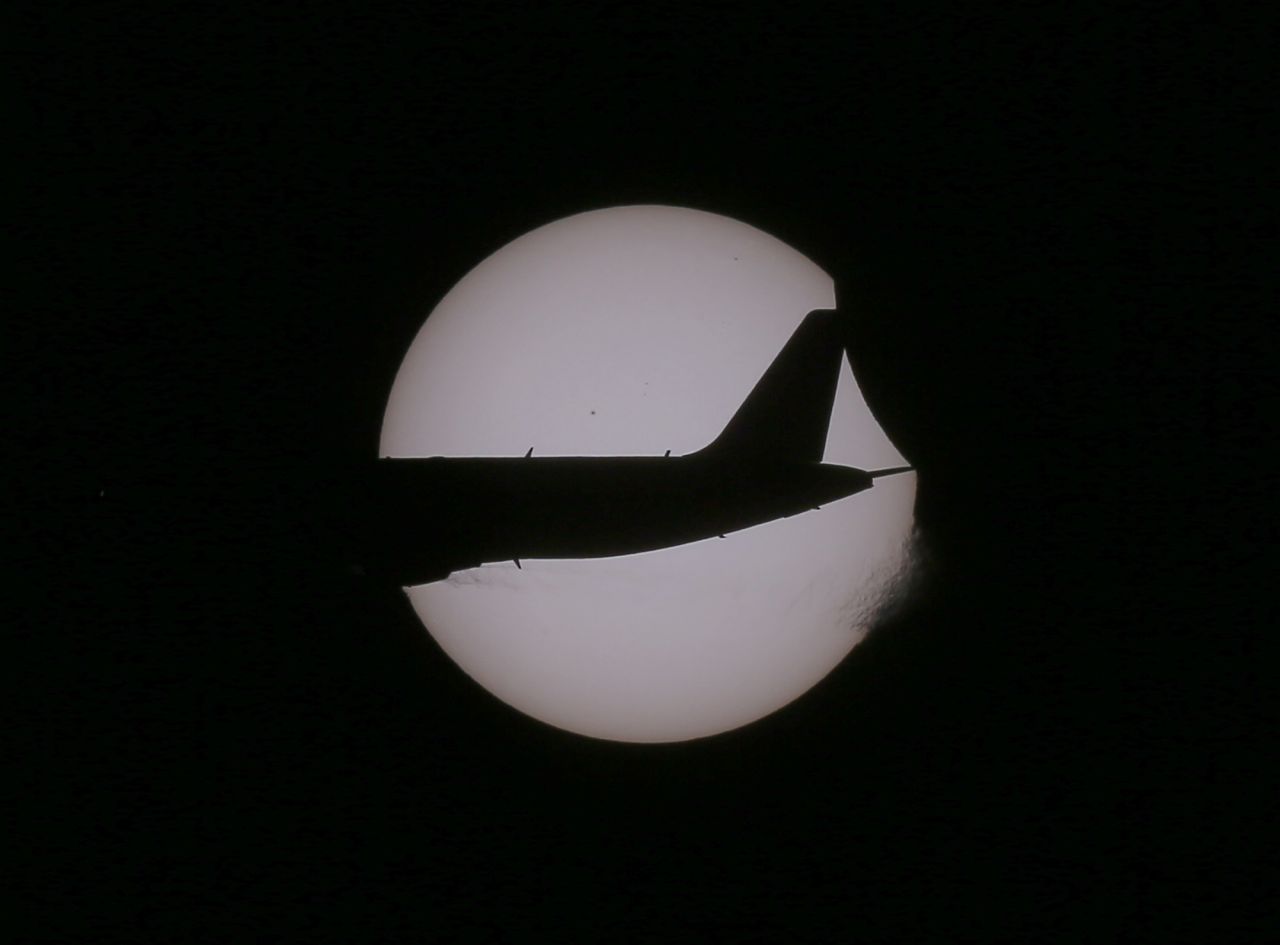 An Air Asia passenger plane flies past the sun as a partial eclipse occurs, seen from Taguig city, east of Manila, Philippines. 