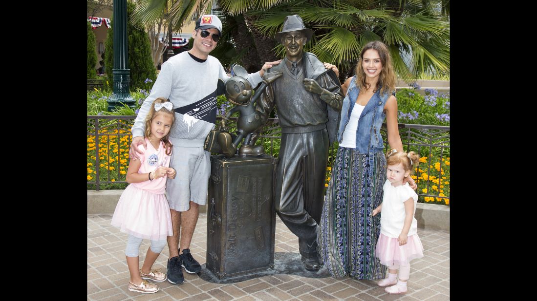 Jessica Alba and husband Cash Warren pose with daughters Haven and Honor Warren with a bronze statue of a young Walt Disney and Mickey Mouse. Alba hired a Spanish professor to teach her and Honor to speak Spanish.