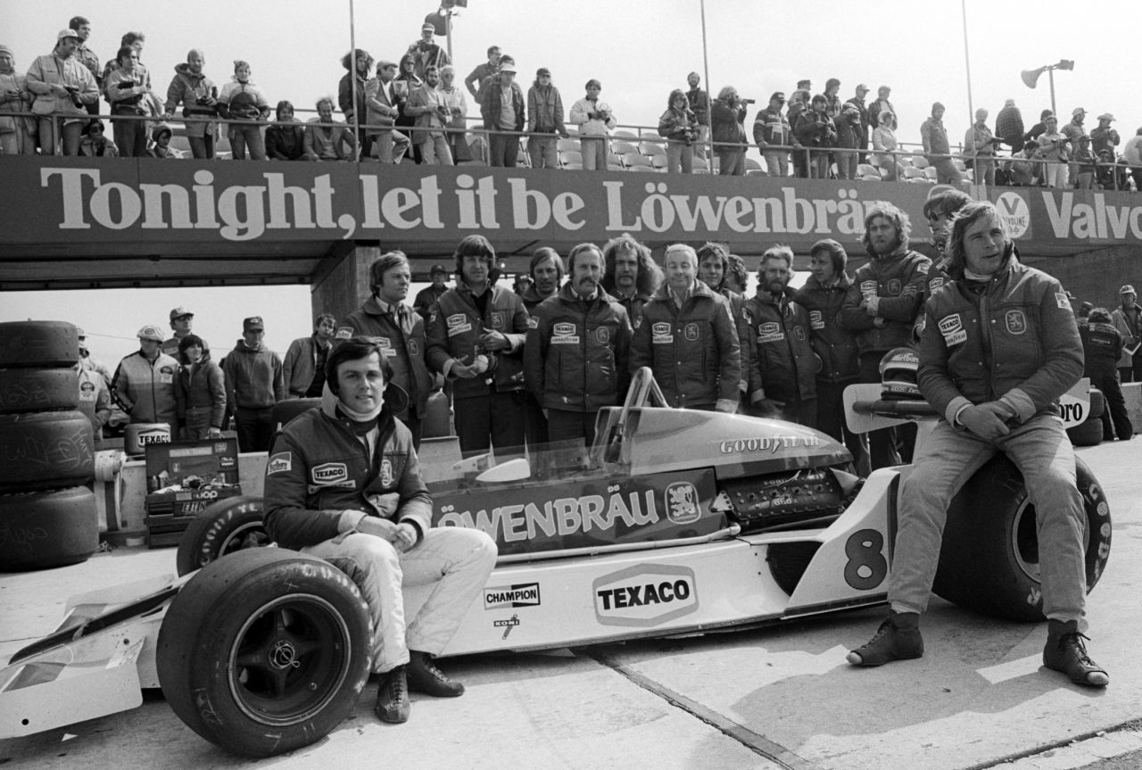 Hunt (right) and French teammate Patrick Tambay (far left) pose with the McLaren M26 car and team at the 1978 United States GP after securing sponsorship from brewer Lowenbrau for the final two races of the season.