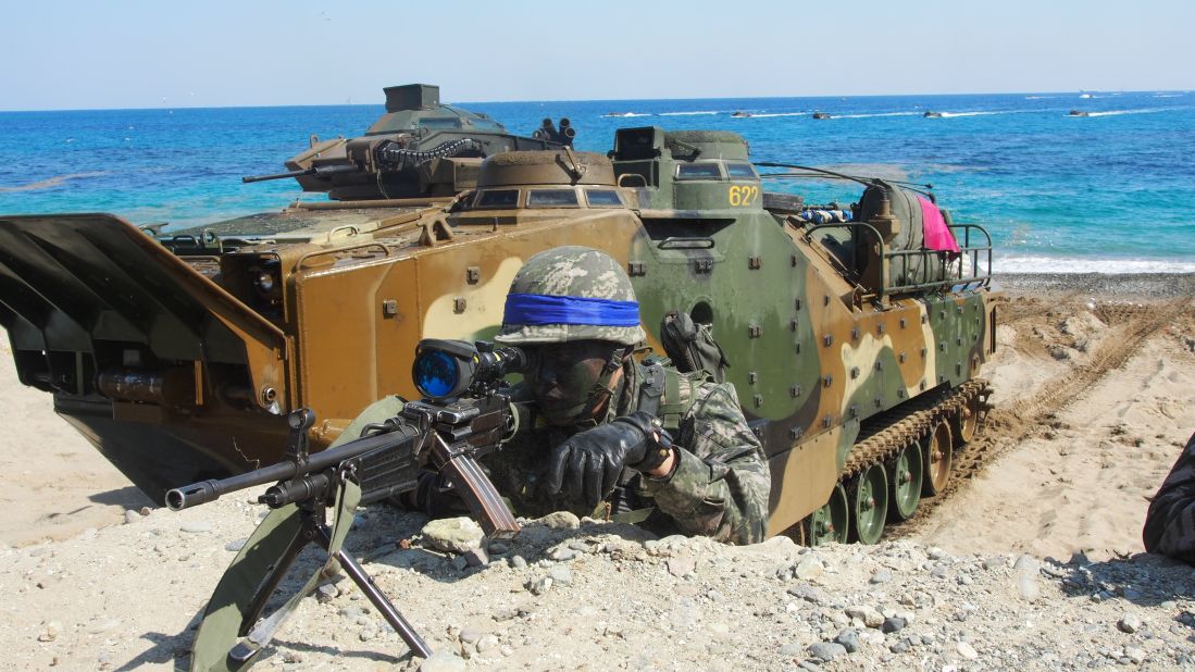 A South Korean Marine looks through his rifle's view finder on March 12 with an amphibious assault vehicle in the background. 