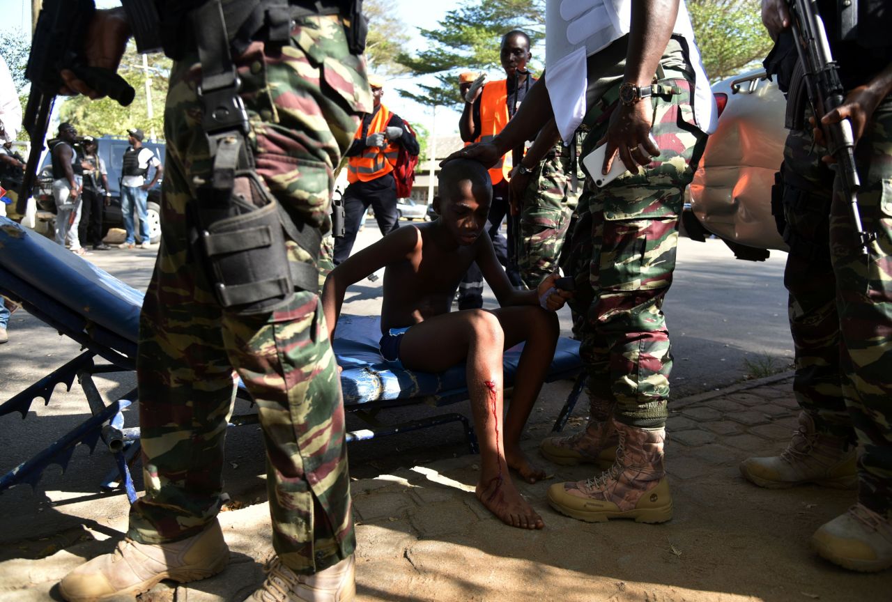 Ivorian soldiers stand around a boy who was injured.