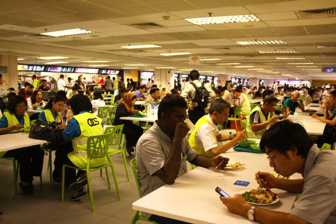 Staff and travelers eat together in the loud and lively food court.