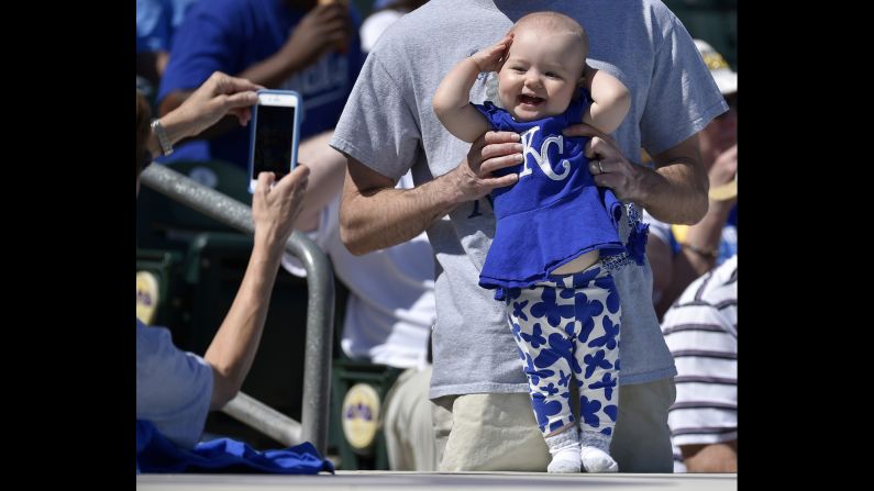 A happy 10-month old Kansas City Royals fan, Sydney Barth, from South Carolina, poses for a photograph on top of the dugout before a spring training game against the Colorado Rockies on Tuesday, March 8, in Surprise, Arizona. 
