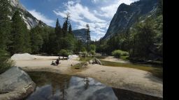 People picnic on the exposed sandy bottom of Mirror Lake that is normally underwater and used by visitors to photograph reflections of the Half Dome rock monolith at Yosemite National Park in California on June 4, 2015.  At first glance the spectacular beauty of the park with its soaring cliffs and picture-postcard valley floor remains unblemished, still enchanting the millions of tourists who flock the landmark every year.But on closer inspection, the drought's effects are clearly visible.      AFP PHOTO/MARK RALSTON        (Photo credit should read MARK RALSTON/AFP/Getty Images)