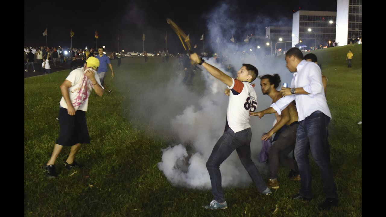Demonstrators throw tear gas back at riot police during a protest in Brasilia on March 16. 