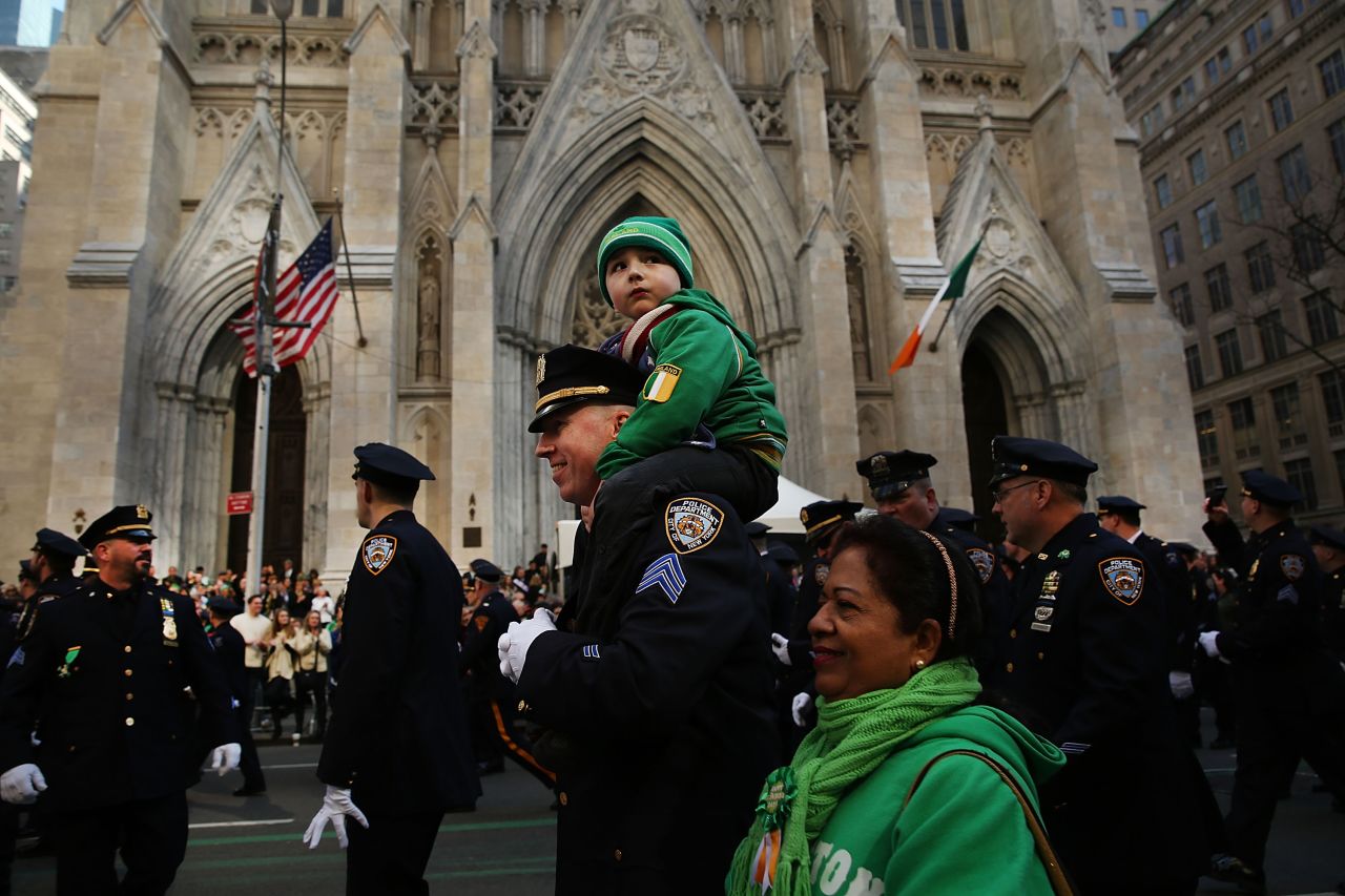 In 2016, an NYPD officer marches with his son past Manhattan's St. Patrick's Cathedral in the annual St. Patrick's Day Parade.