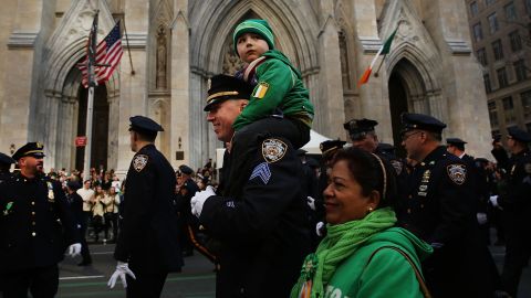 In 2016, an NYPD officer marches with his son past Manhattan's St. Patrick's Cathedral in the annual St. Patrick's Day Parade.