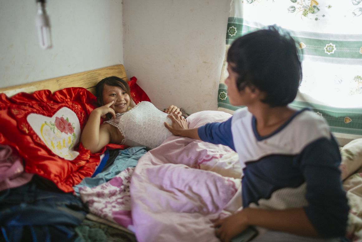 Wen, 18, touches the pregnant belly of his 13-year-old wife Jie. They live together in Tangzibian village, Mengla county in Yunnan.