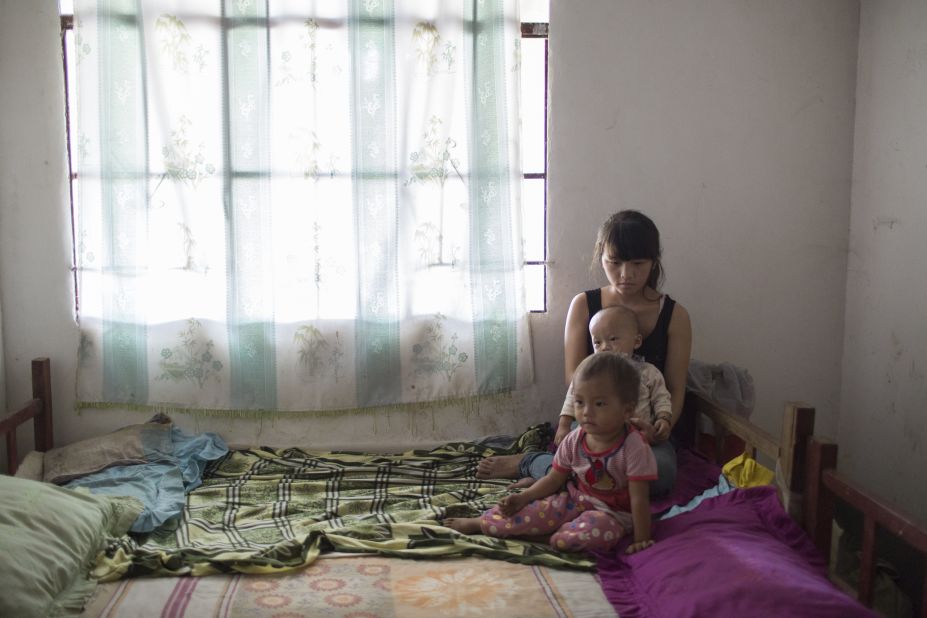 Mei, 16, sits on bed with her 2-year-old daughter and 1-year-old son in Wanhe village, Mengla county, Yunnan province. She has been married for 2 years. She and her husband were classmates in primary school and they dropped out from school after getting married.