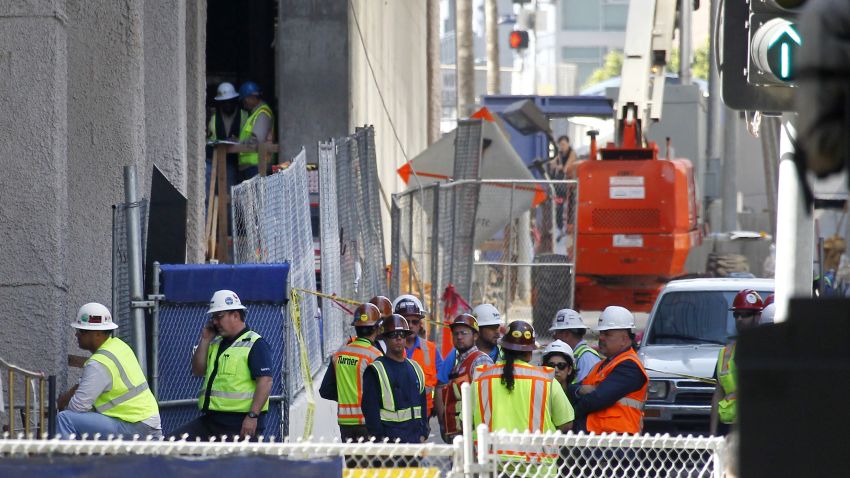 Construction workers gather at the base of the Wilshire Grand Tower on South Figueroa Street where a worker fell to his death on Thursday, March 17, 2016. A fire department spokesperson said the the construction worker plunged 50 stories to his death from the building under construction and hit the back of a passing car in downtown Los Angeles. (AP Photo/Nick Ut)