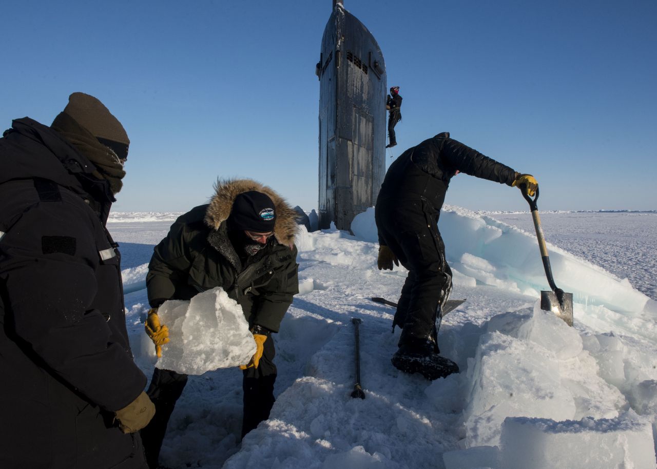 Sailors and civilians, assigned to Arctic Submarine Lab, clear the ice from the hatch of USS Hampton (SSN 767).