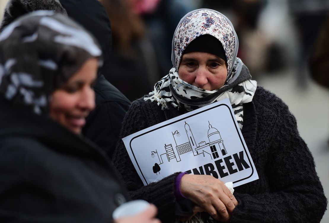 A woman holds a piece of paper reading "Molenbeek" during a candlelit vigil to the victims of the Paris attacks in Brussels.