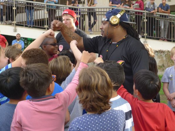 Marshawn Lynch teaches the kids at the camp how to fist bump.