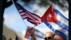 MIAMI, FL - DECEMBER 20: A protester holds an American flag and a Cuban one as she joins with others opposed to U.S. President Barack Obama's announcement earlier in the week of a change to the United States Cuba policy stand together at Jose Marti park on December 20, 2014 in Miami, Florida. President Obama announced a move toward normalizing the relationship with Cuba after a swap of prisoners took place. (Photo by Joe Raedle/Getty Images)