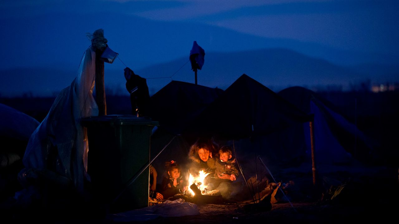 A woman sits with children around a fire at the northern Greek border point of Idomeni in March 2016.