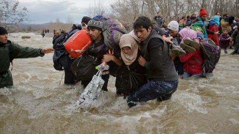 Migrants stumble as they cross a river north of Idomeni, Greece, attempting to reach Macedonia on a route that would bypass the border-control fence in March 2016.