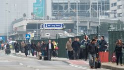 People walk away from Brussels airport after explosions rocked the facility.