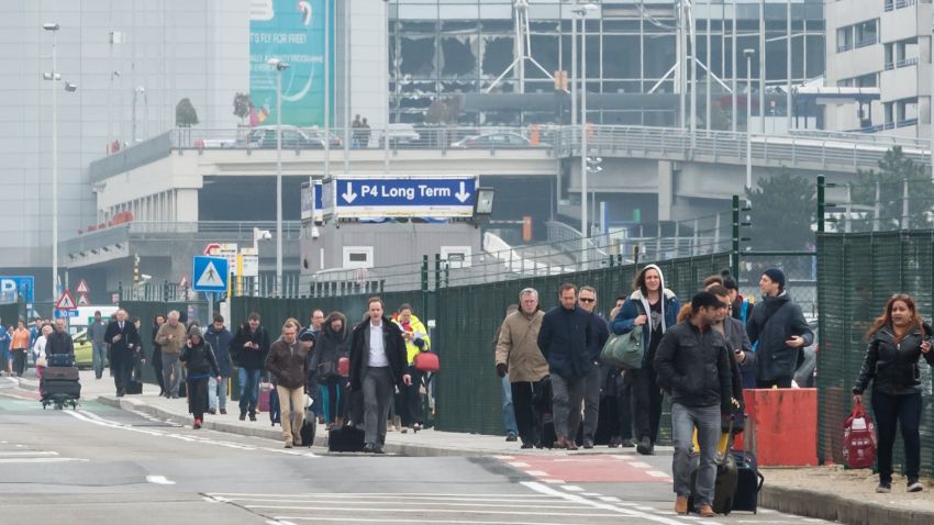 People walk away from Brussels airport after explosions rocked the facility.
