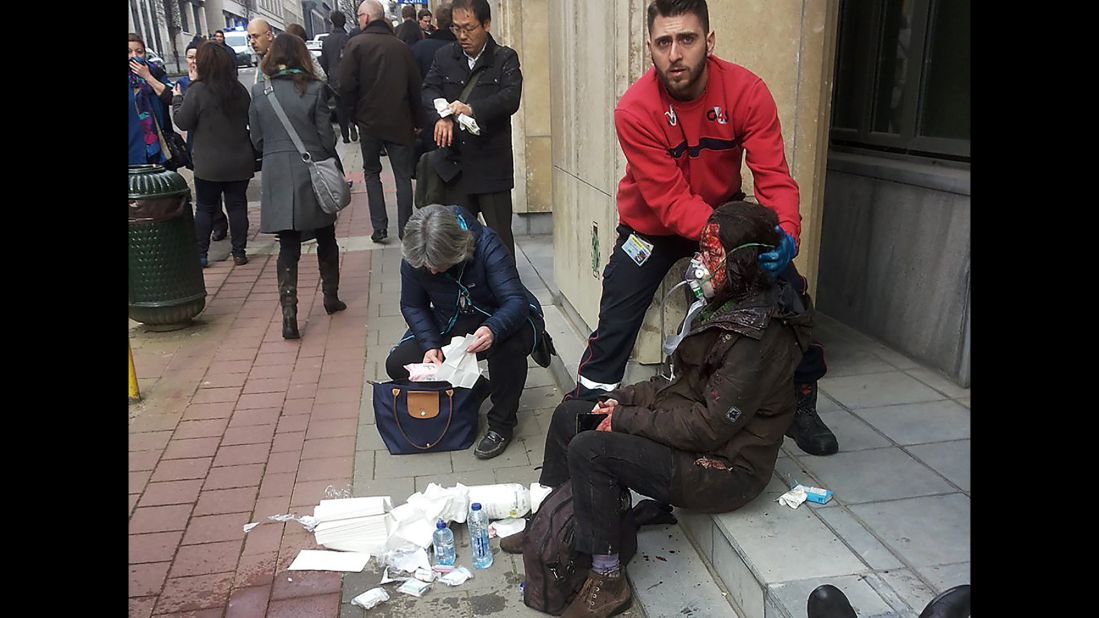 A private security guard helps a wounded woman outside the Maelbeek metro station.