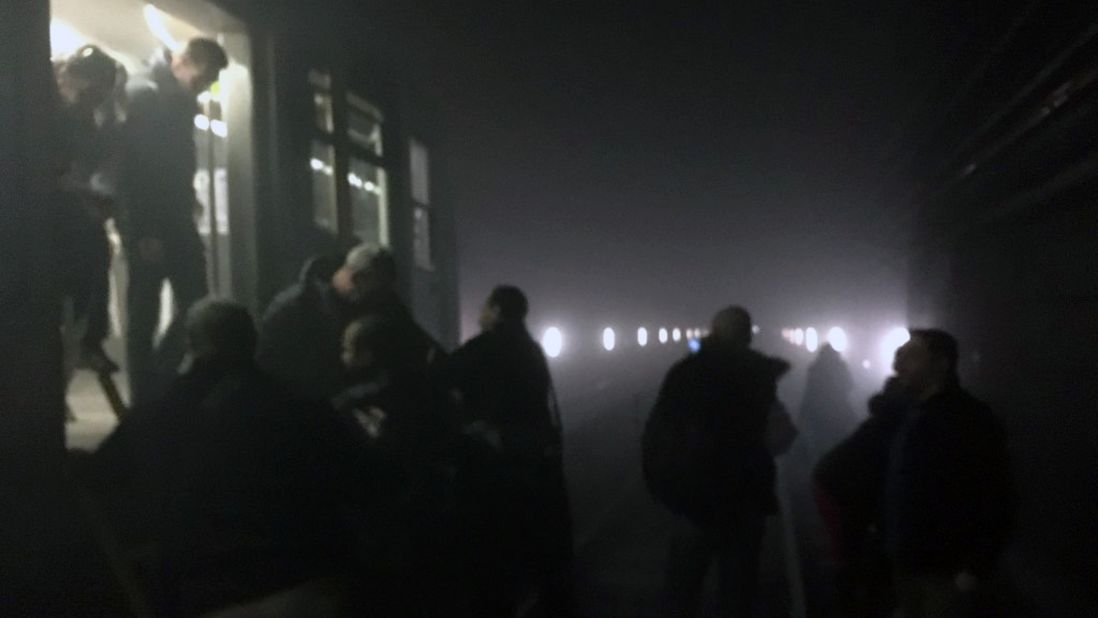 Subway passengers walk along the tracks following a blast at the Maelbeek metro station.