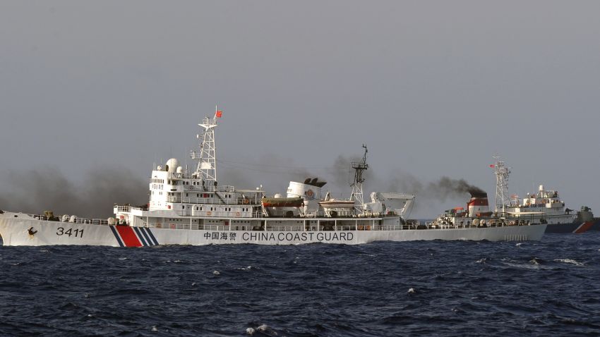 This picture taken from a Vietnam Coast Guard ship on May 14, 2014 shows a Vietnamese Coast Guard ship (R, dark blue) speeding up away from a  China Coast Guard ship  near to the site of a Chinese drilling oil rig (R, background) being installed at the disputed water in the South China Sea off Vietnam's central coast. Vietnam National Assembly's deputies gathered for their summer session are discussing the escalating tension with China over the South China Sea's contested water. AFP PHOTO/HOANG DINH Nam        (Photo credit should read HOANG DINH NAM/AFP/Getty Images)