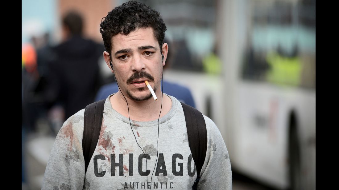 A man with blood stains on his sweater leaves the airport.