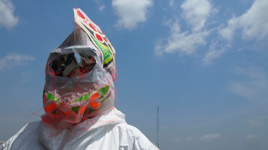 The exhibition looks at masks as social commentary and critique. Pictured: A video still from the film "An Ancestor Takes a Photograph" (2014), filmed in Nigeria. Visual artist and performer Wura-Natasha Ogunji brings a troupe of women to the streets of Lagos to perform masquerade (a traditionally male enterprise) to challenge gender roles in Africa. 