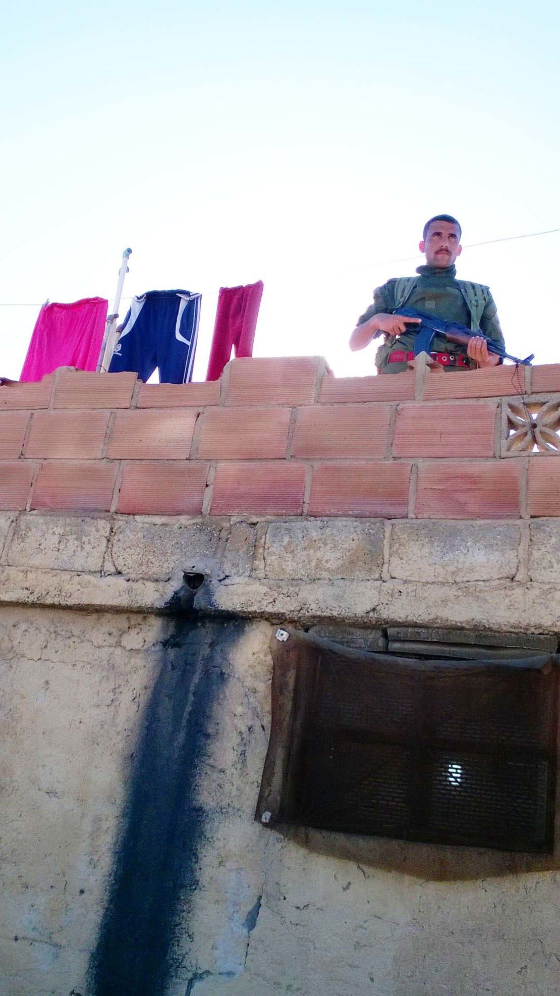 Life in the embattled community: A patrolling soldier stands next to a line of washing.