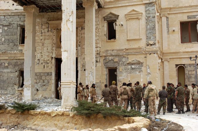 Syrian troops stand next to a mansion belonging to the Qatari royal family on March 24.
