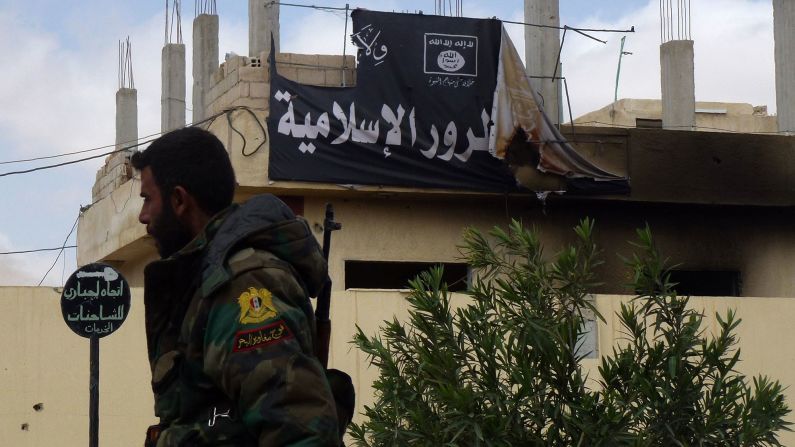 A member of the Syrian military walks past a banner bearing ISIS slogans on March 27.