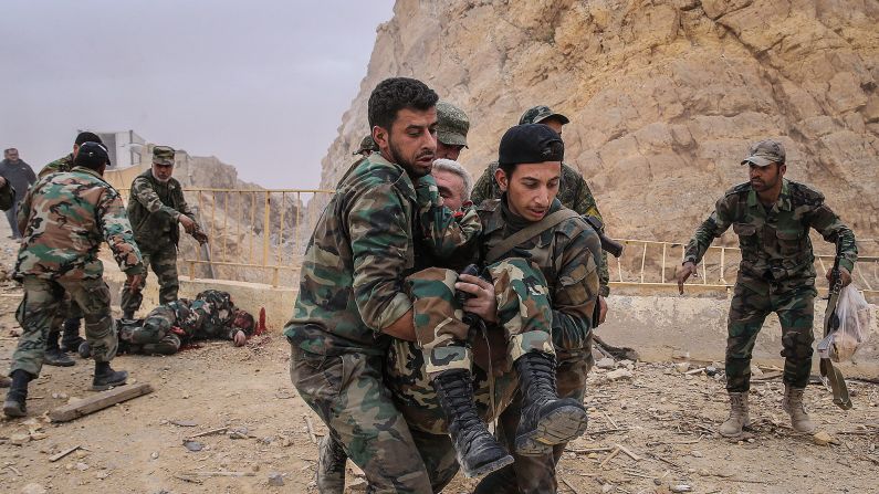 Syrian soldiers carry a wounded comrade after an explosion near the castle on Saturday, March 26.