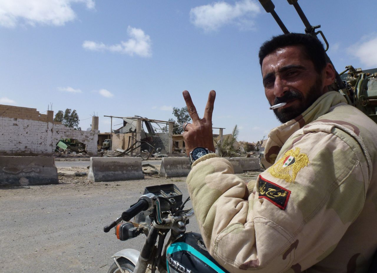 A member of the Syrian pro-government forces flashes the V-sign in a residential neighborhood of the modern town of Palmyra.
