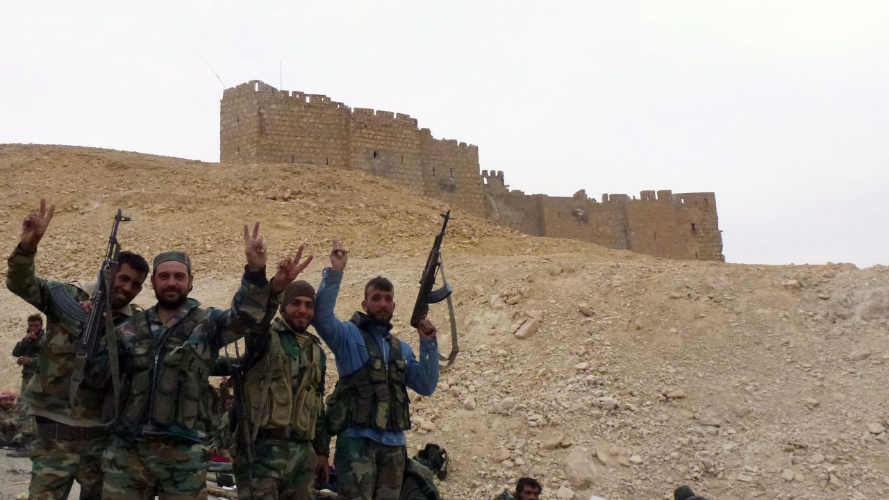 Syrian pro-governement forces gesture next to the Palmyra citadel on March 26, 2016, during a military operation to retake the ancient city from the jihadist Islamic State (IS) group. / AFP / Maher AL MOUNES        (Photo credit should read MAHER AL MOUNES/AFP/Getty Images)