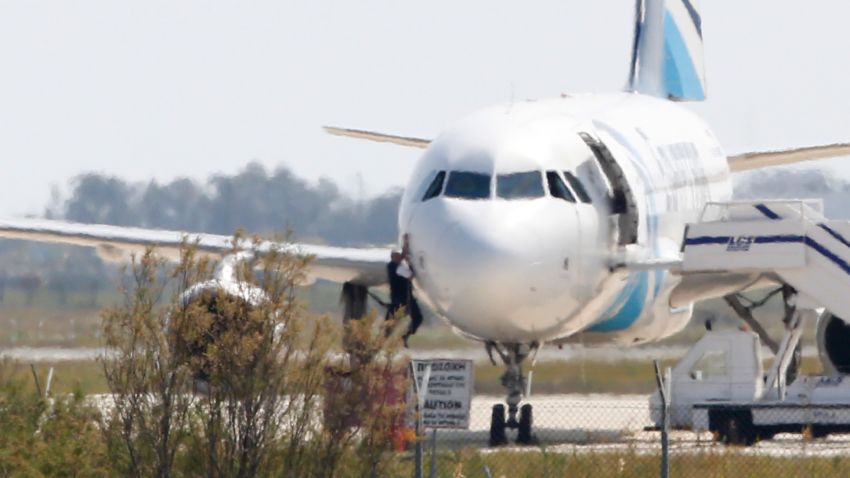 A man climbs out of the cockpit window an EgyptAir Airbus A-320 parked at the tarmac of Larnaca airport after being hijacked and diverted to Cyprus on March 29, 2016.
The hijacker who seized the Egyptian airliner and forced it to land in Cyprus has been detained, Cypriot government spokesman Nicos Christodoulides said. / AFP / BEHROUZ MEHRI (Photo credit should read BEHROUZ MEHRI/AFP/Getty Images)
