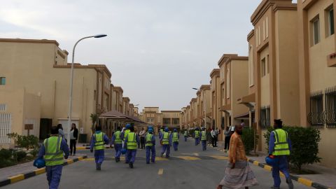 Des ouvriers étrangers travaillant sur le chantier de construction du stade de football al-Wakrah, l'un des stades de la Coupe du monde 2022 au Qatar, rentrent à pied dans leur logement. 