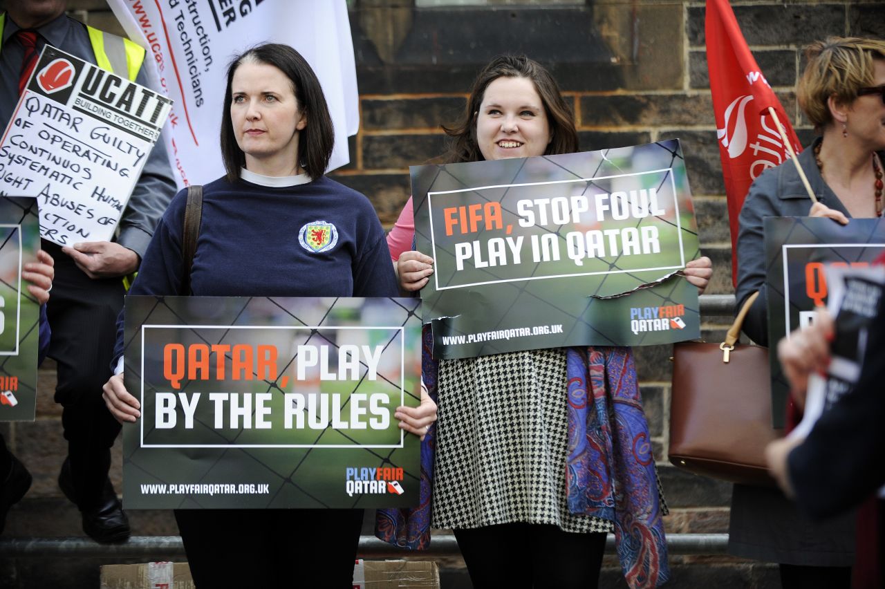 Demonstrators hold placards calling for change to Qatar's policies on the working conditions of migrant workers ahead of the international friendly between Scotland and Qatar in Edinburgh in June 5, 2015. 