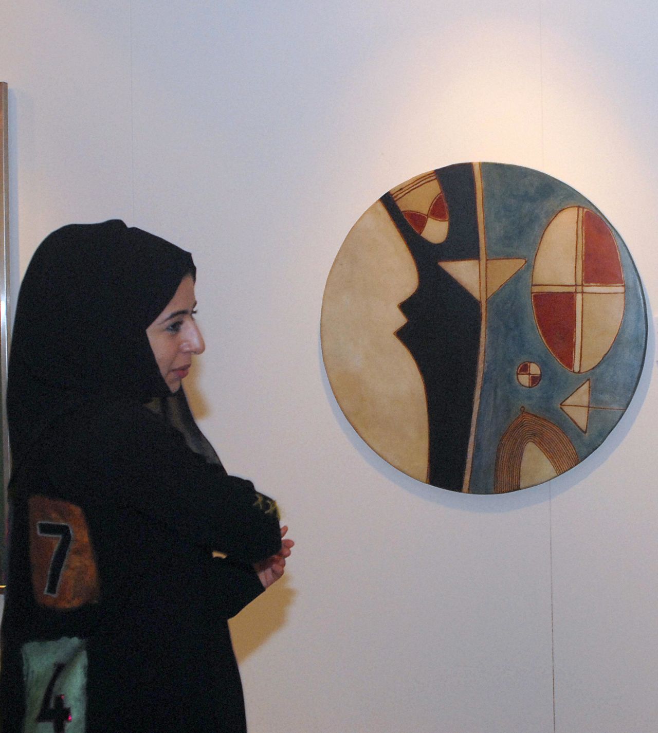 A woman is seen next to an art work by Farid Belkahia of Morocco before Christie's first public Modern and Contemporary art sale in the Middle East in 2006.